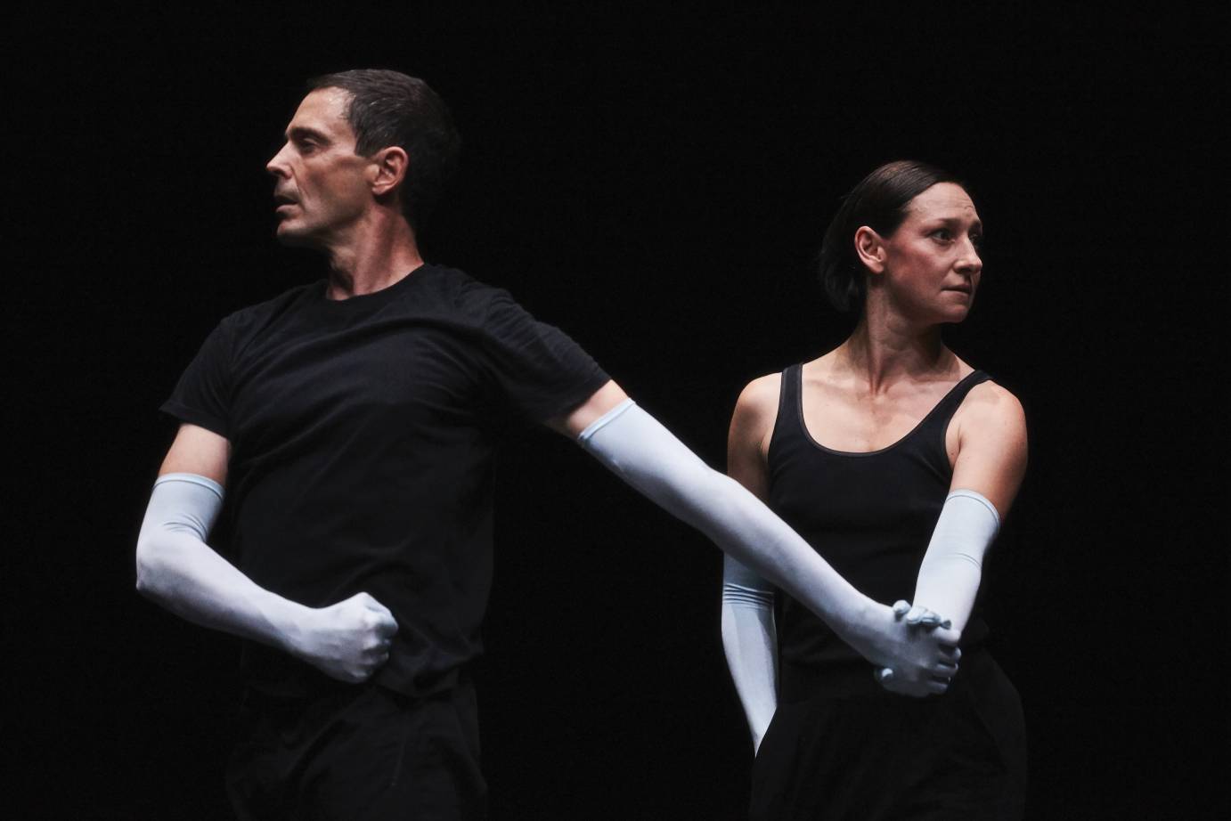 Two dancers in ice blue gloves look opposite directions